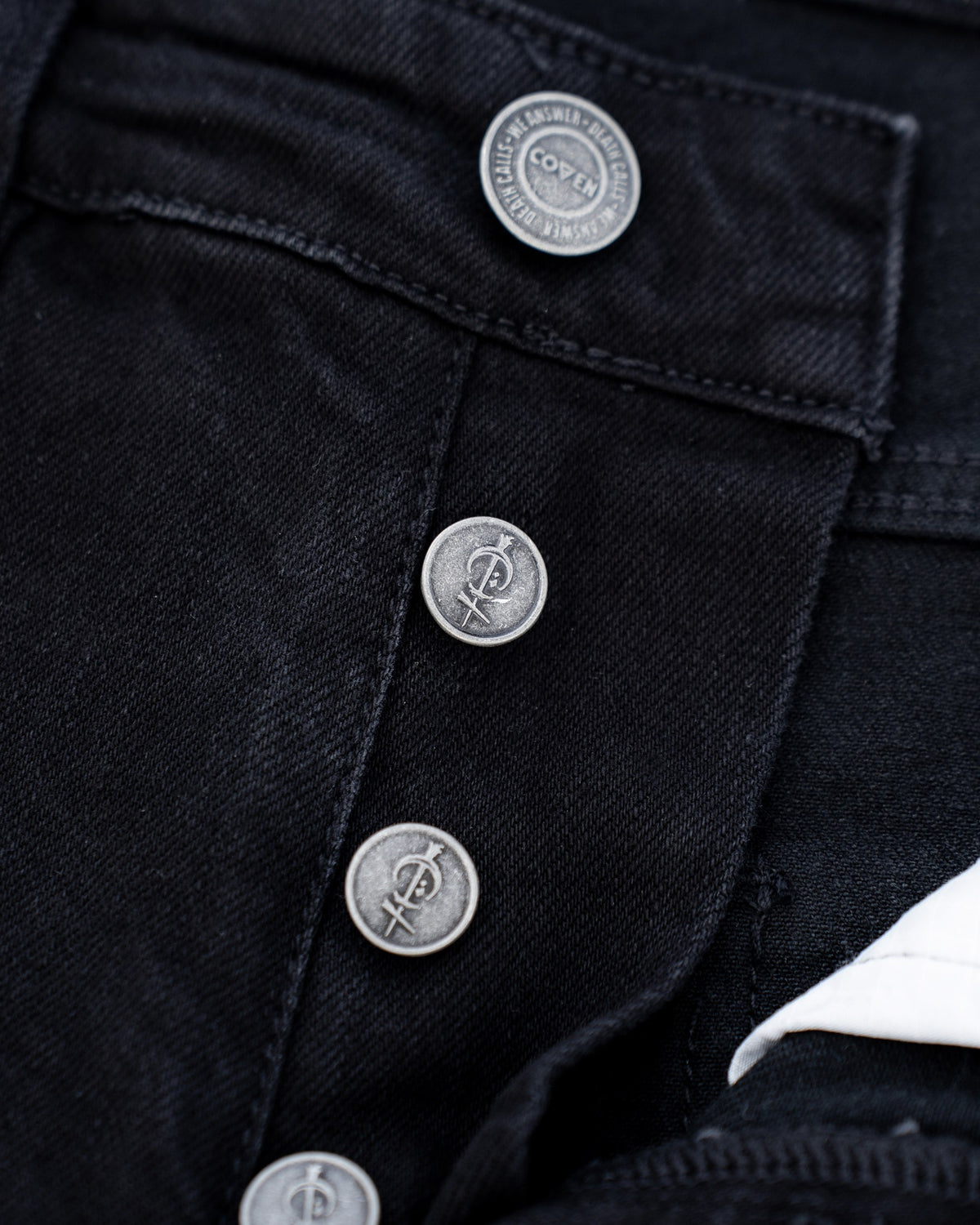 The Wormskin Jeans in Schwarz, Knopfleiste geschlossen mit geprägten COVEN Knöpfen
