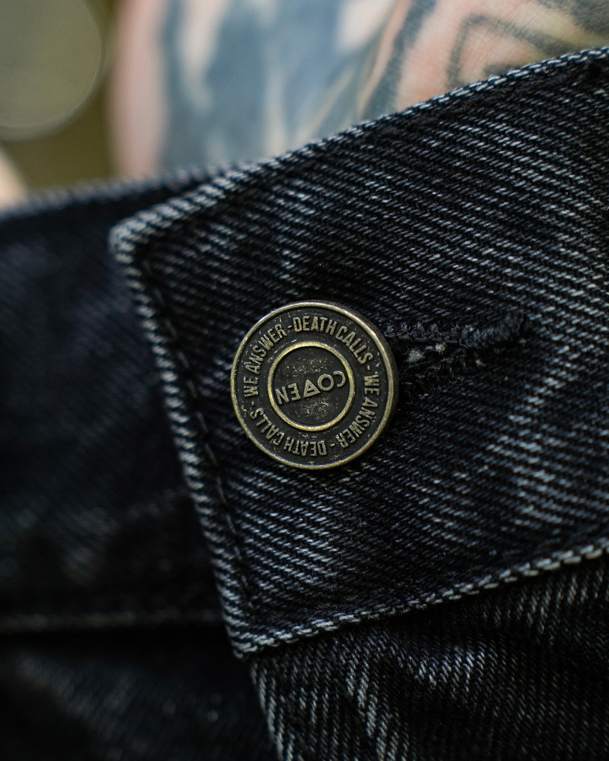 Metallknopf im Detail der schwarzen COVEN Trucker Jacket 'Kunduz Drift'
