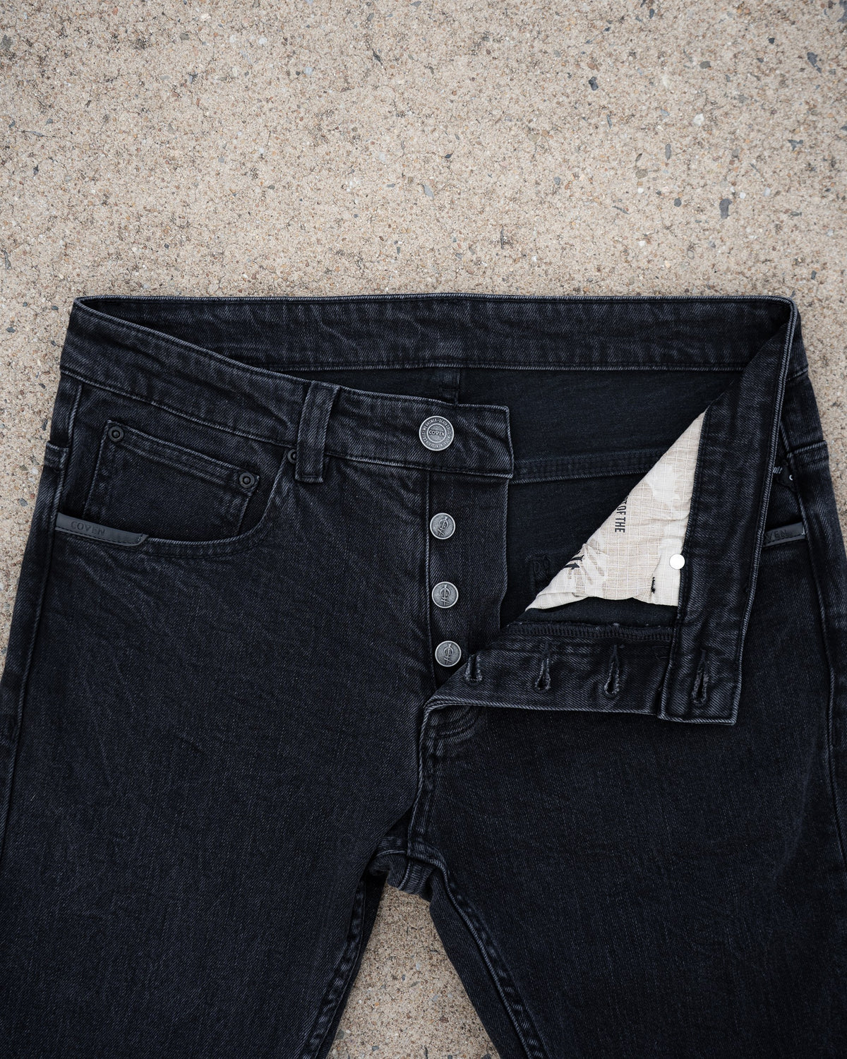 The Wormskin Jeans in Washed Black, Vorderansicht mit geöffneter Knopfleiste und Innenfutter