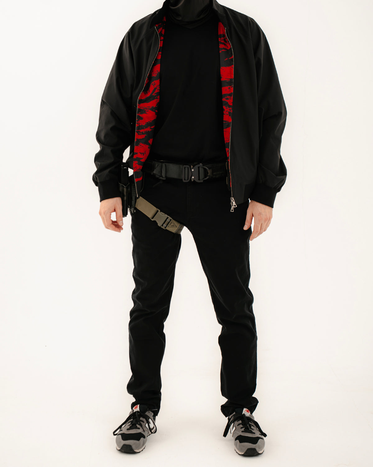 The Pariah Harrington Jacke in Schwarz am Model, Ganzkörperaufnahme mit Battle Belt und Beinholster