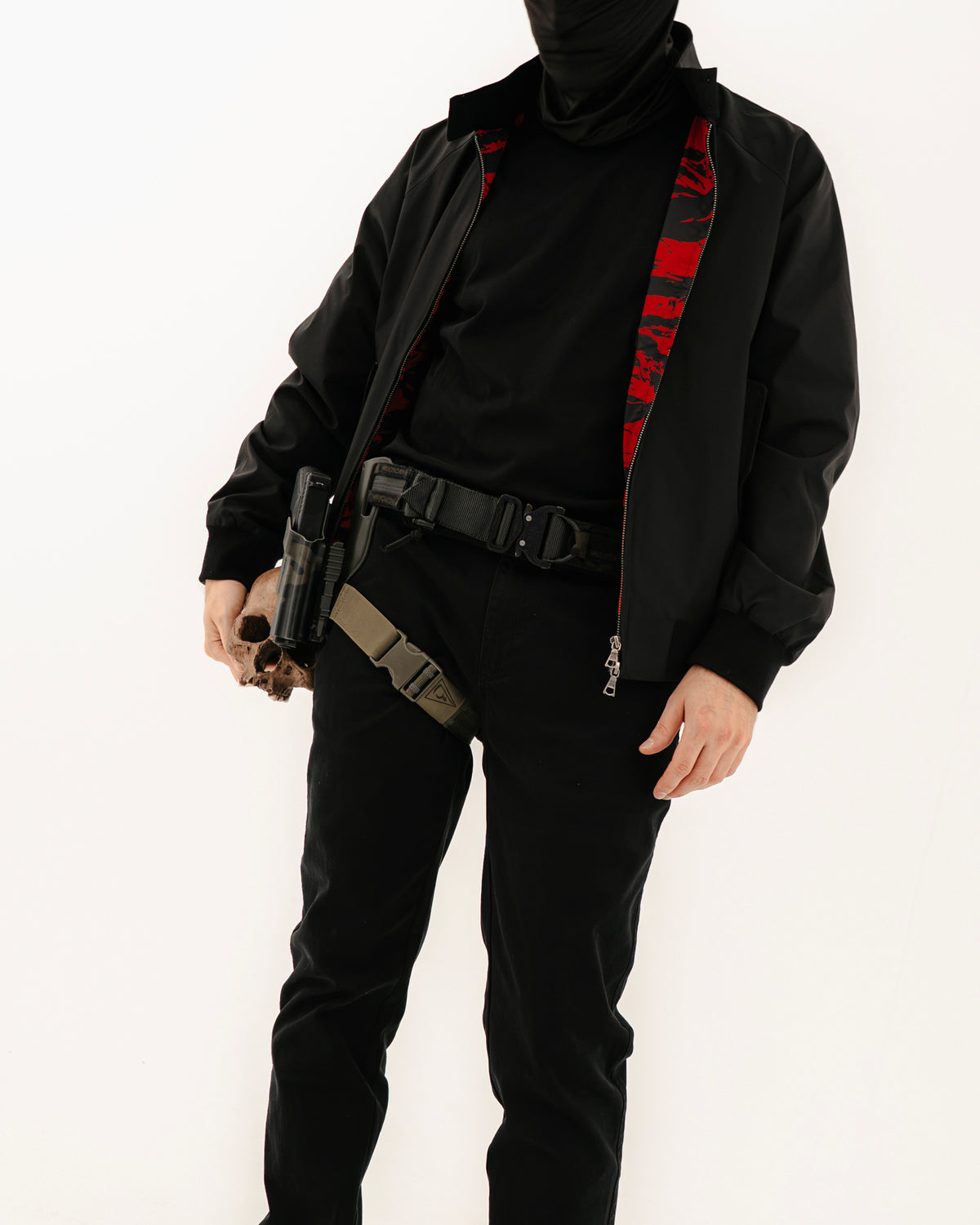The Pariah Harrington Jacke in Schwarz am Model, Ganzkörperaufnahme in Dreiviertelansicht mit Battle Belt