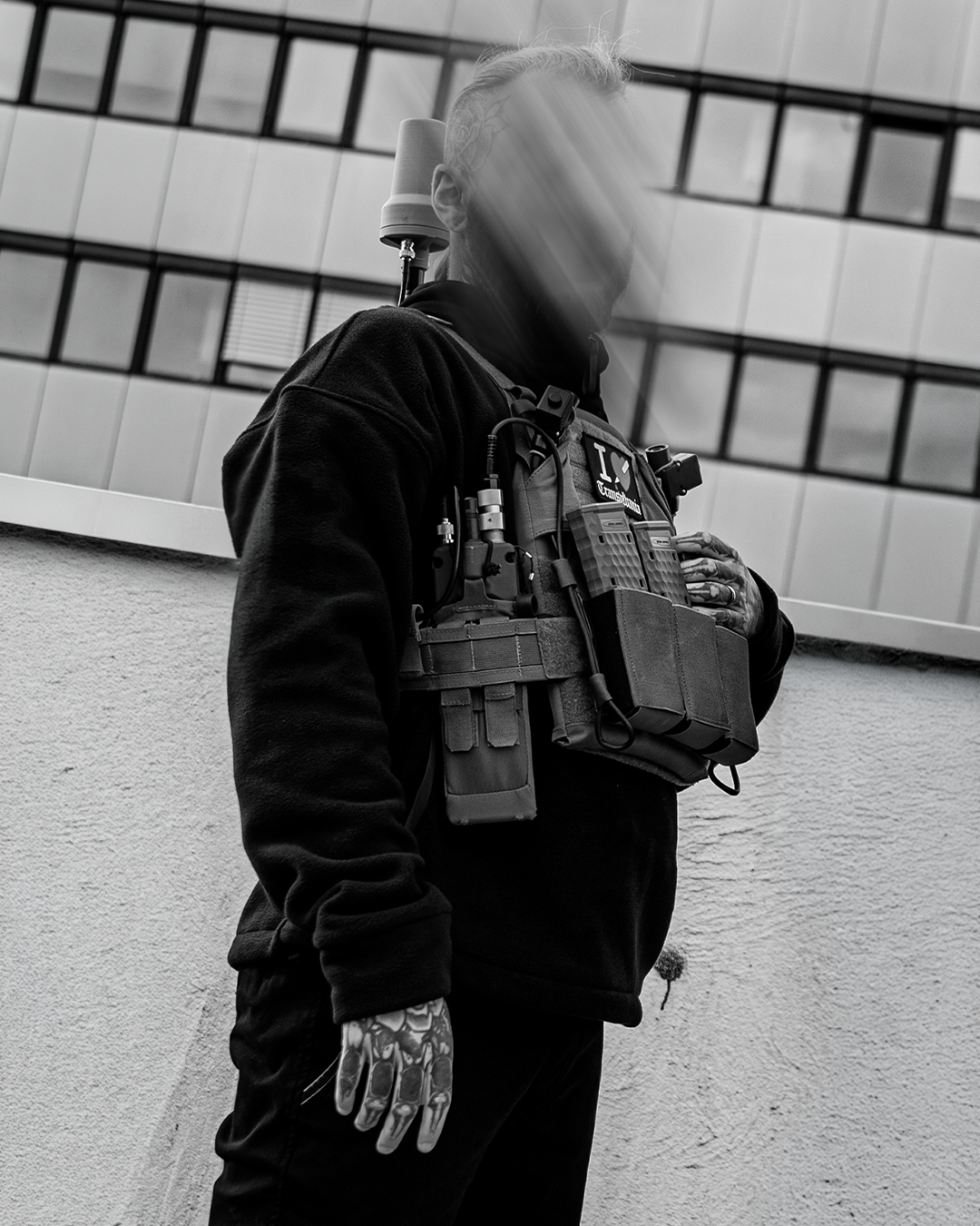 Iscariot Oversize 1/2 Zipper getragen, Seitenansicht mit Plattenträger vor Betonfassade
