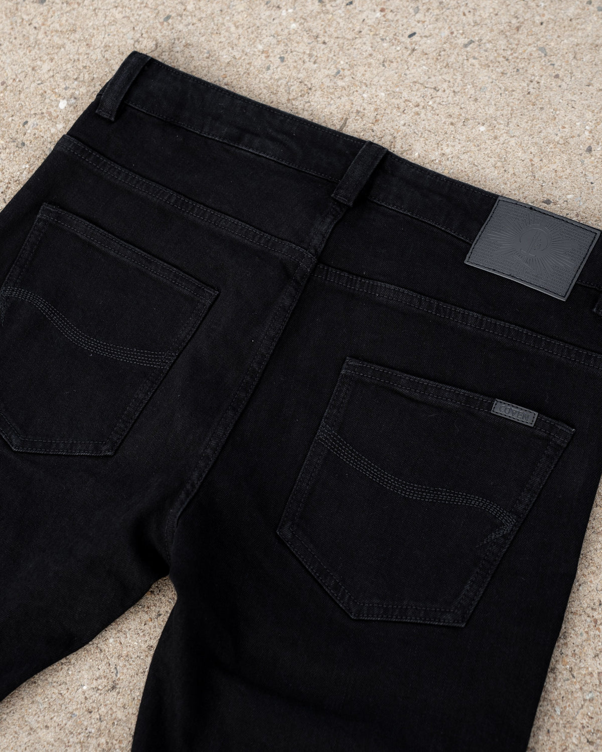 The Wormskin Jeans in Schwarz, Rückansicht schräg mit Gesäßtasche und Lederpatch am Bund