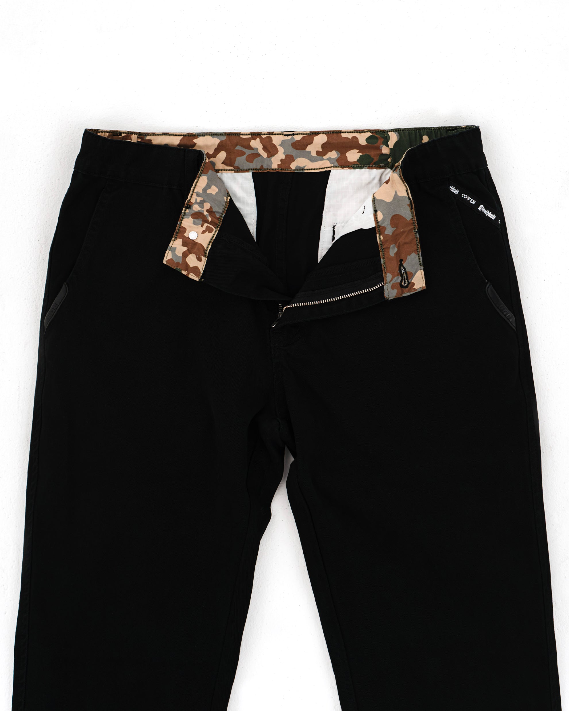 Dead Drop Chino Aeon Coven Camo in Schwarz, geöffneter Bund mit Coven-Camo-Innenfutter und Knopfleiste