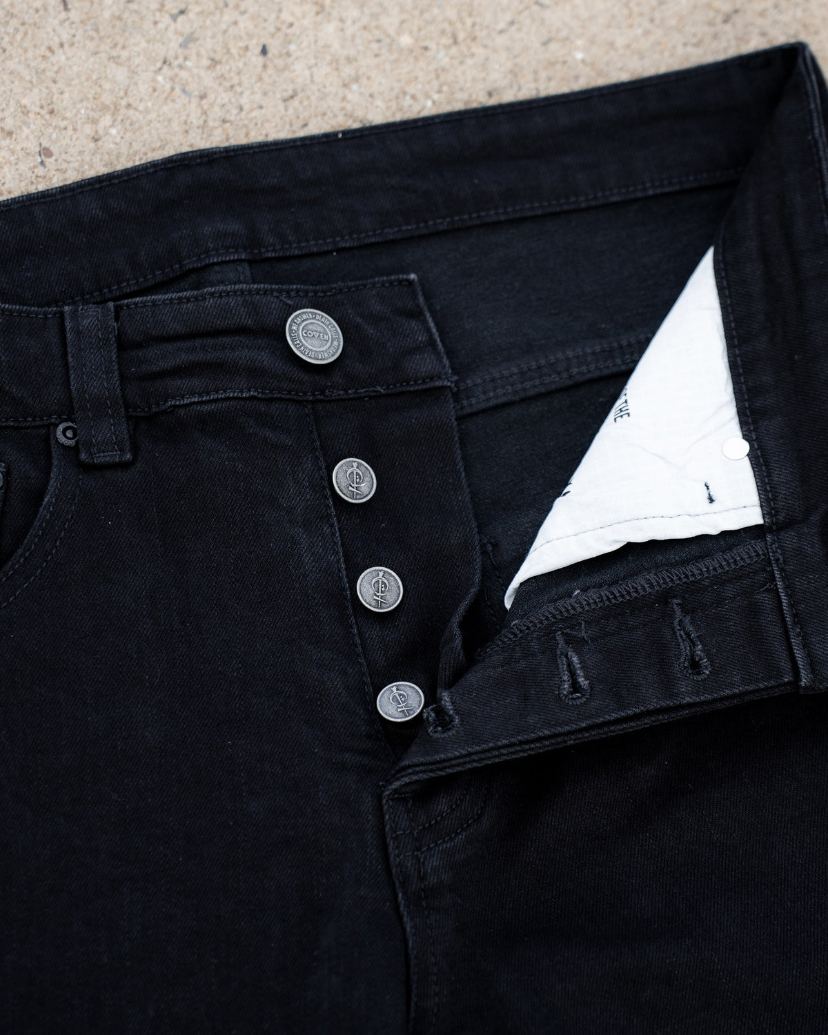 The Wormskin Jeans in Schwarz, geöffnete Knopfleiste mit hellem Innenfutter