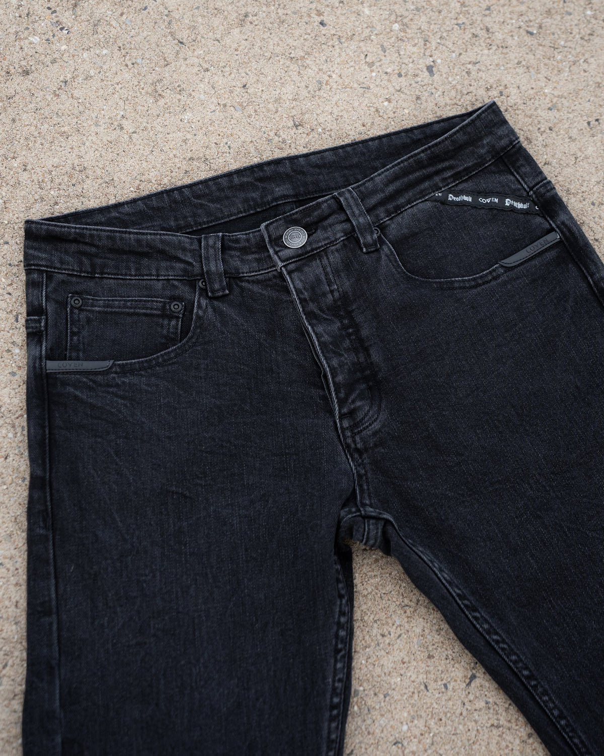 The Wormskin Jeans in Washed Black, Vorderansicht schräg mit Knopfleiste und Taschen
