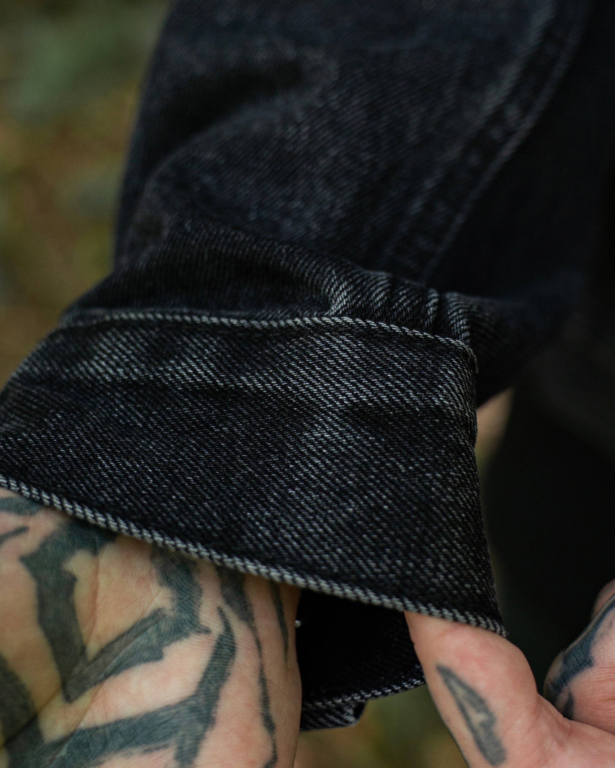 Denim-Detail am Saum der schwarzen COVEN Trucker Jacket 'Kunduz Drift'