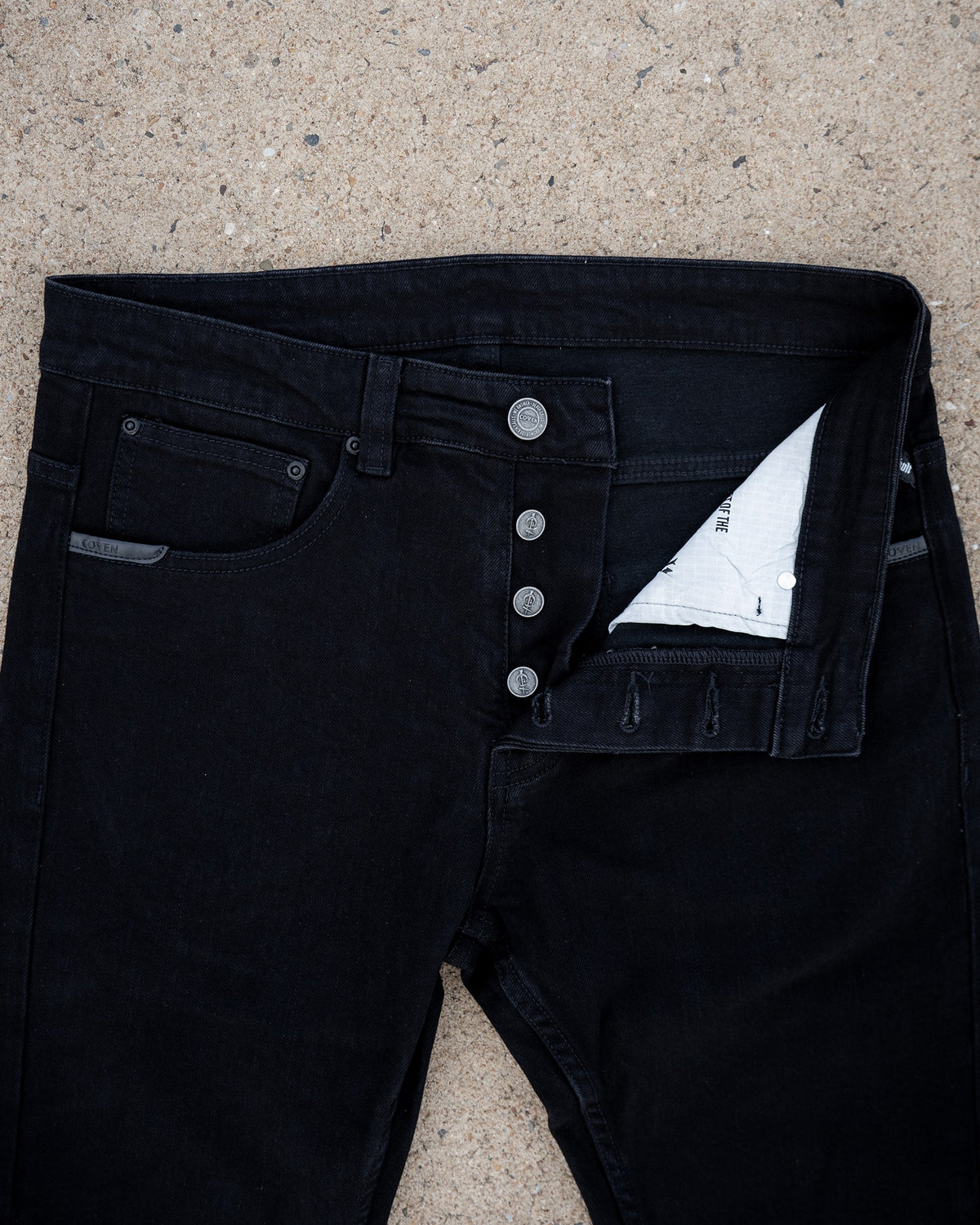 The Wormskin Jeans in Schwarz, Vorderansicht mit geöffneter Knopfleiste und Innenfutter