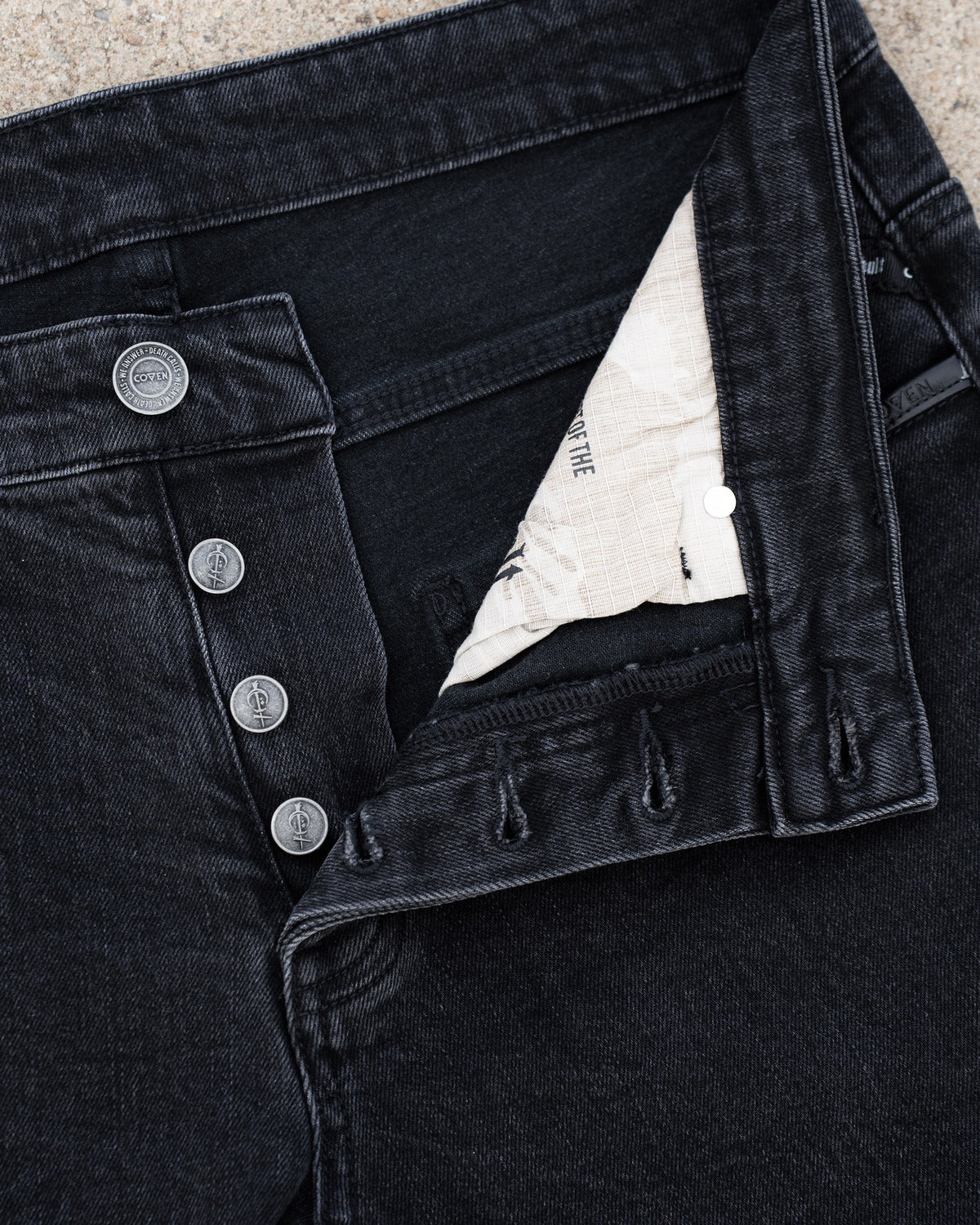 The Wormskin Jeans in Washed Black, geöffnete Knopfleiste mit hellem Innenfutter