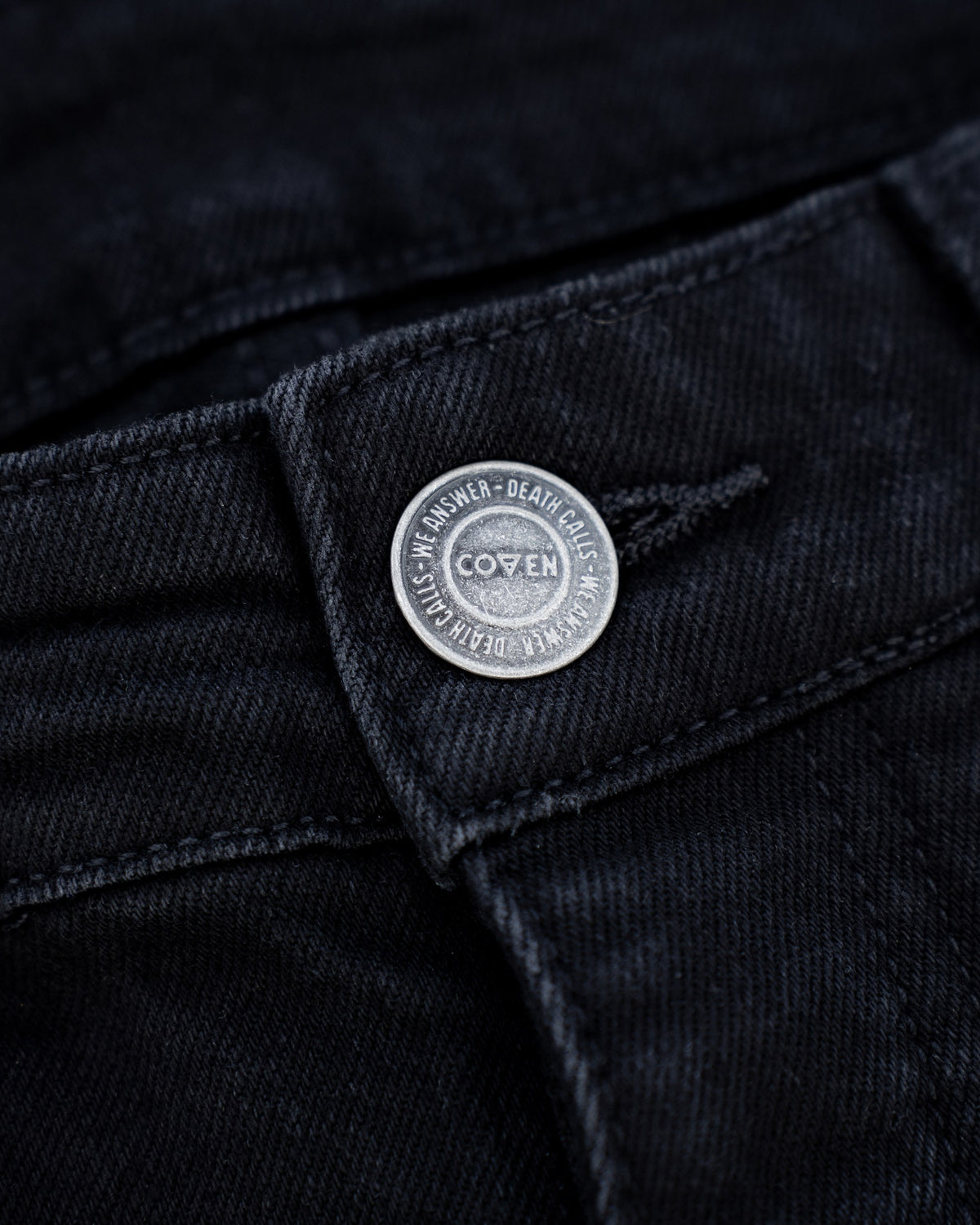 The Wormskin Jeans in Schwarz, Taillenknopf im Makro mit Prägung Death calls - we answer