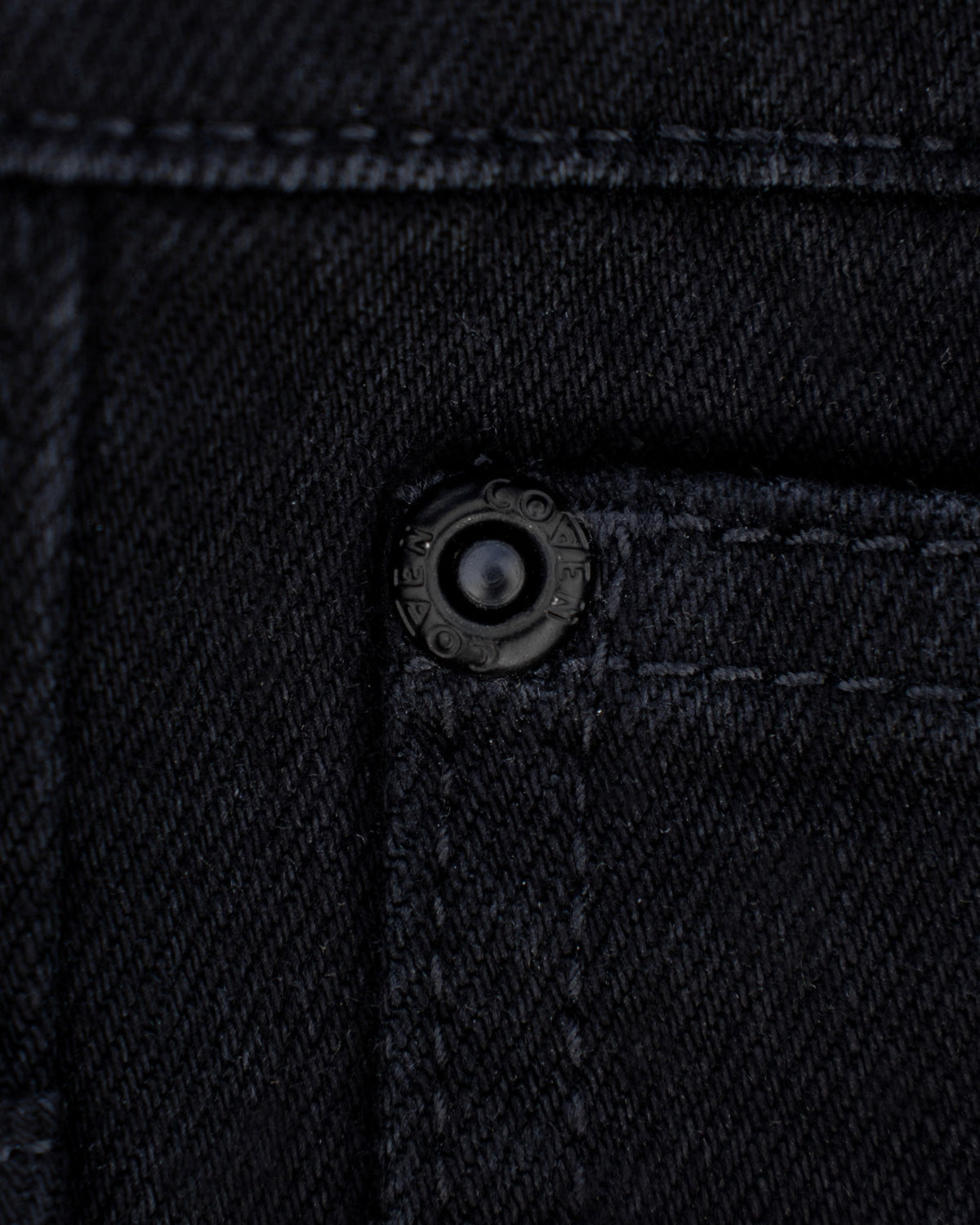 The Wormskin Jeans in Schwarz, verdeckter Druckknopf an der Tasche im Detail