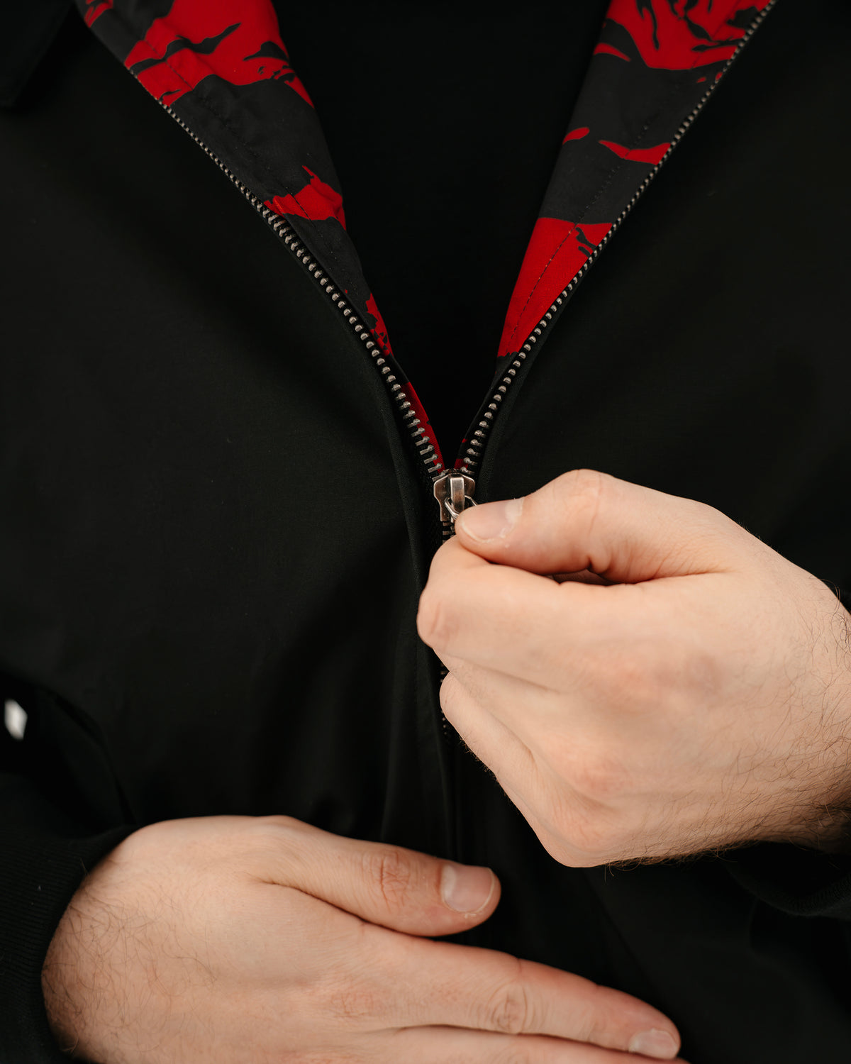 The Pariah Harrington Jacke in Schwarz am Model, YKK Reißverschluss im Detail mit Tiger Stripe Red Futter