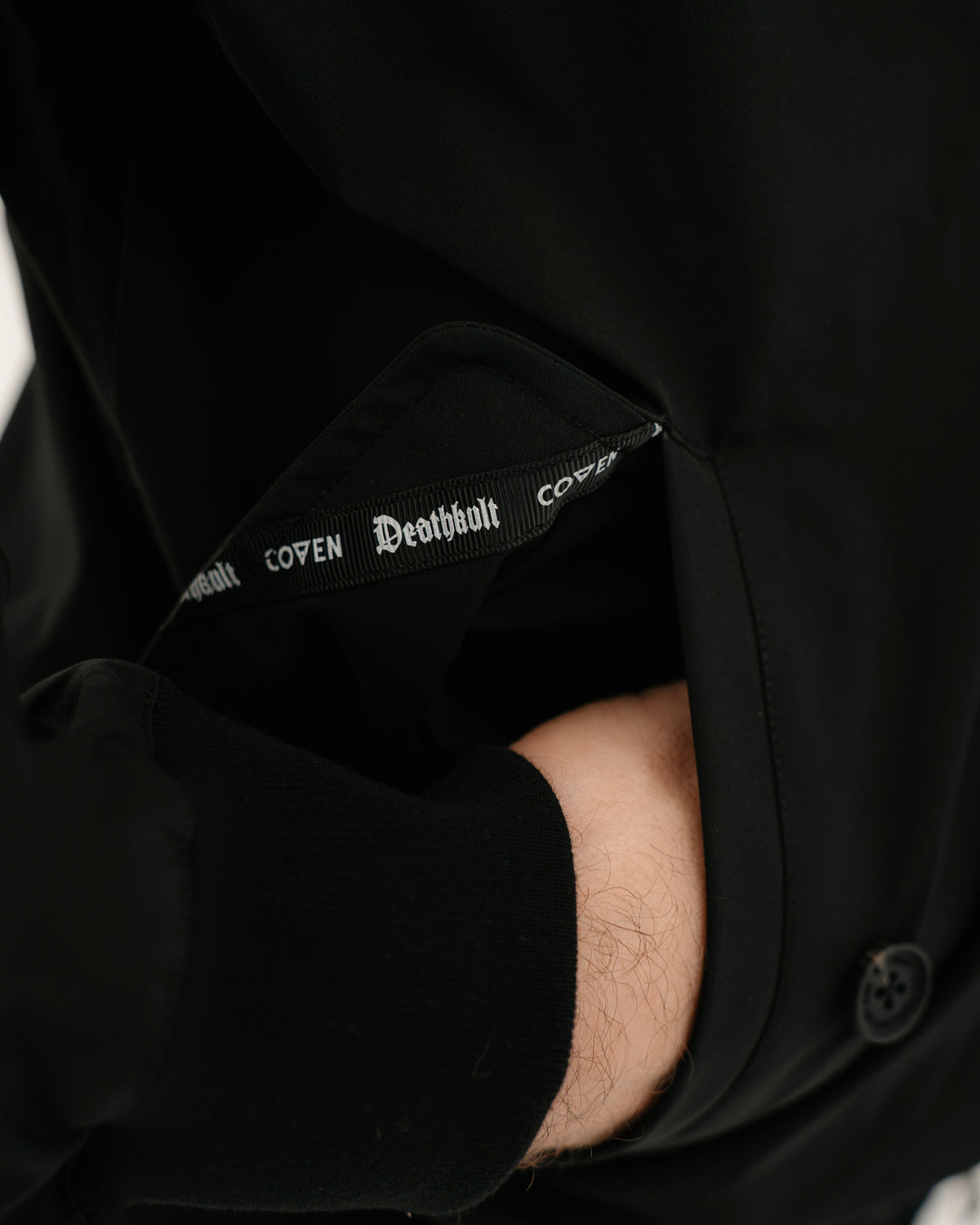 The Pariah Harrington Jacke in Schwarz am Model, COVEN Deathkult Webband an der Innenseite des Ärmels
