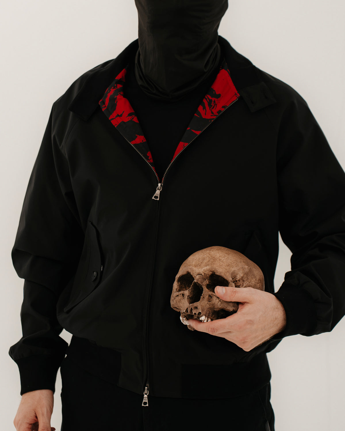 The Pariah Harrington Jacke in Schwarz am Model, Oberkörper mit Totenschädel in der Hand