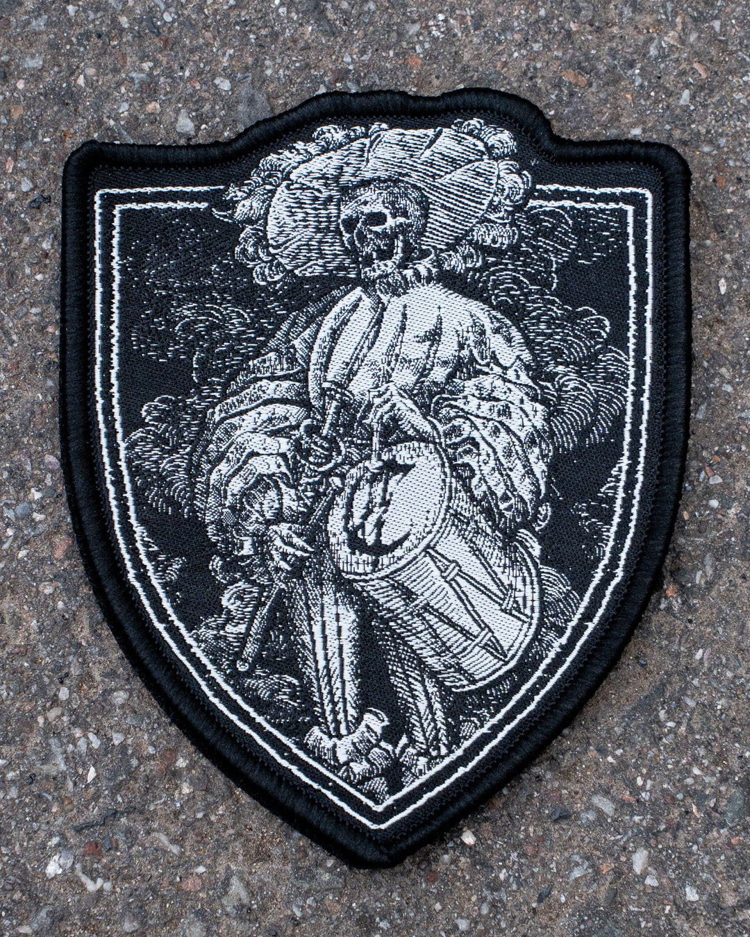 Bis die Trommel schweigt Patch von COVEN, Trommler mit Federhut auf Wappenschild in Schwarz-Weiß