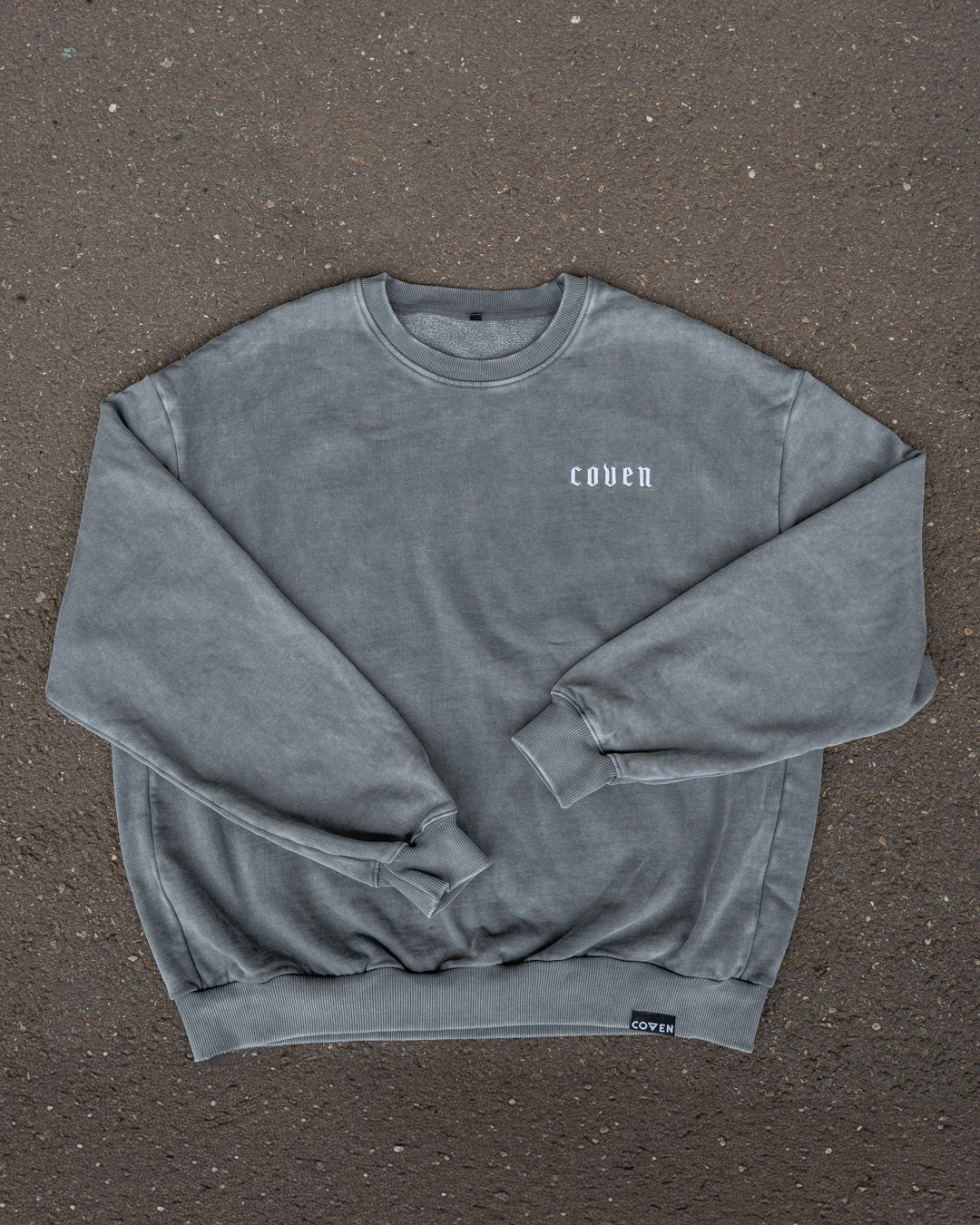 Santa Muerte Heavy Oversize Sweatshirt flach liegend auf Asphalt, Vorderseite mit COVEN Brustdruck